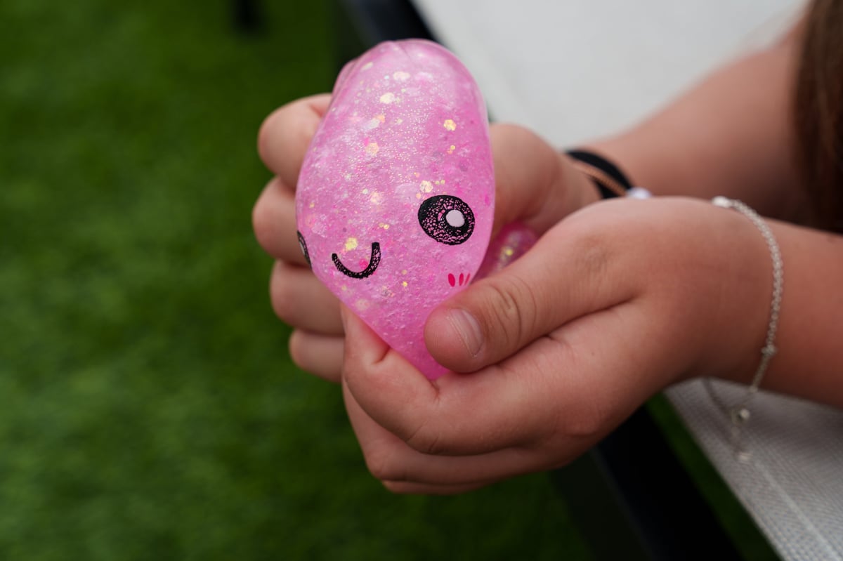 A child squeezing a pink glitter squishy dumpling toy