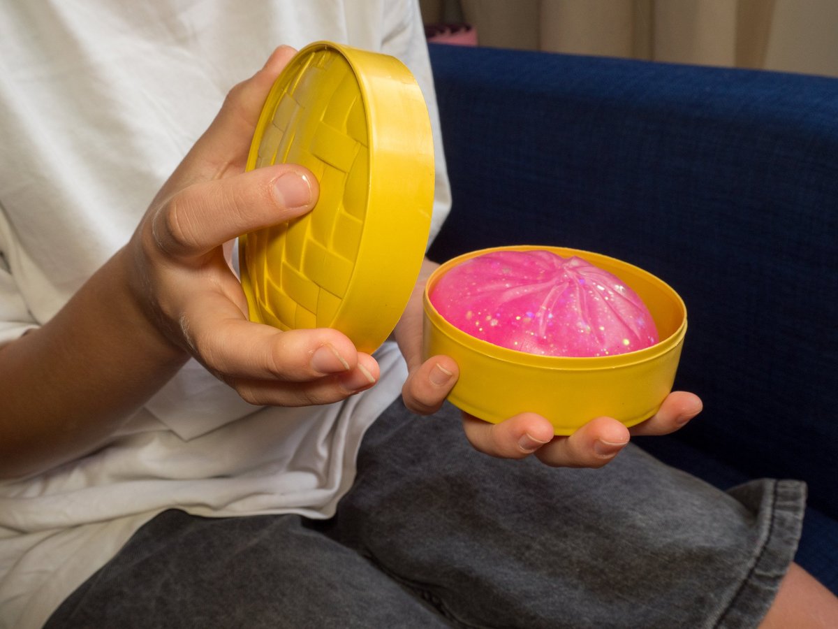 A child unboxing a pink glittery squishy dumpling toy