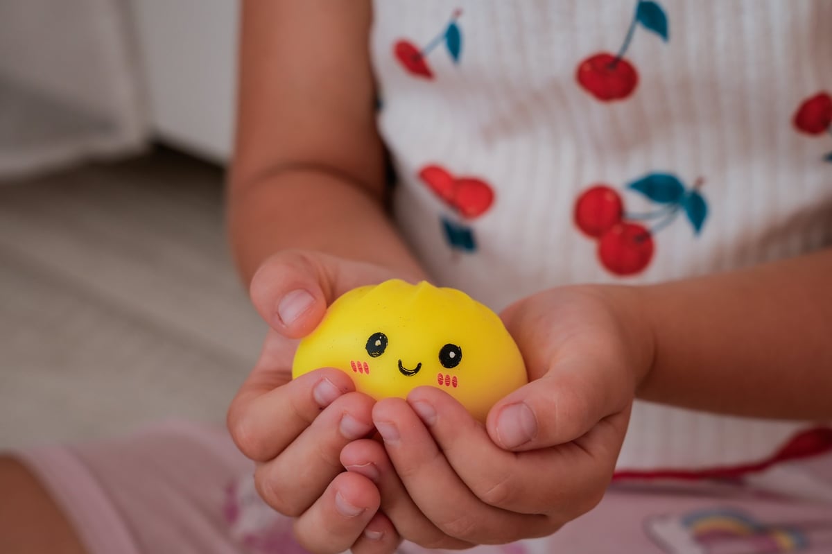 A child holding a dumpling-shaped squishy toy in both hands
