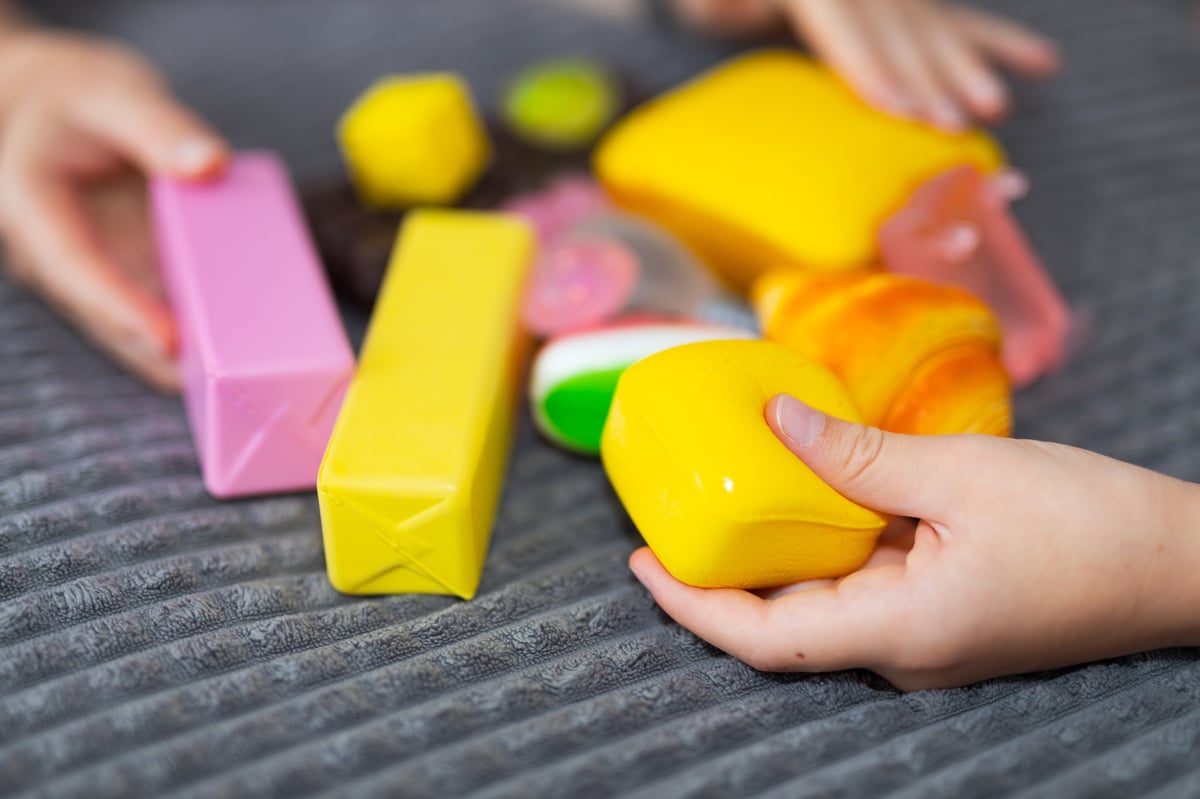 Children's hands holding a pile of bright, colourful squishy sensory toys